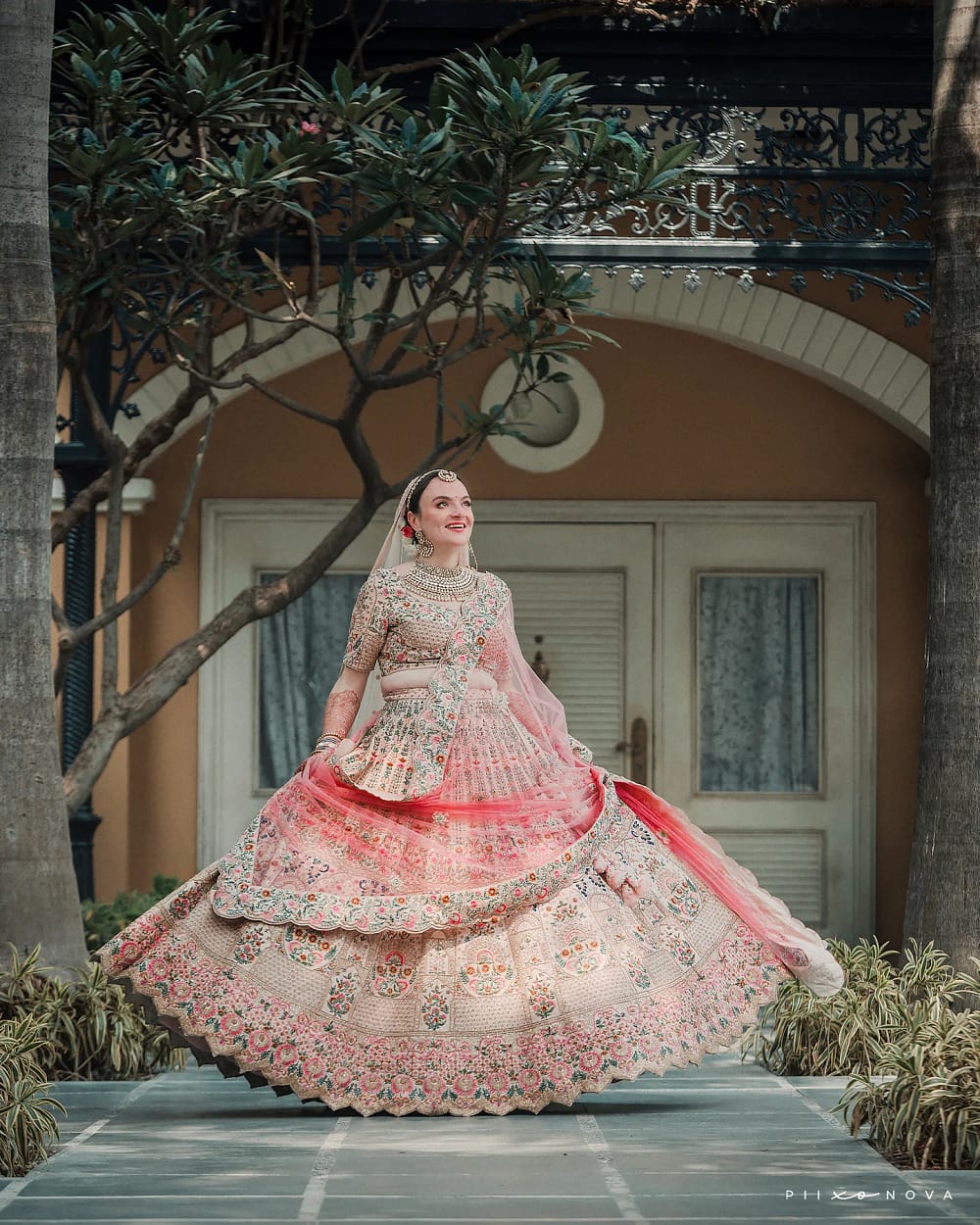 A bride twirling in a pink and gold lehenga