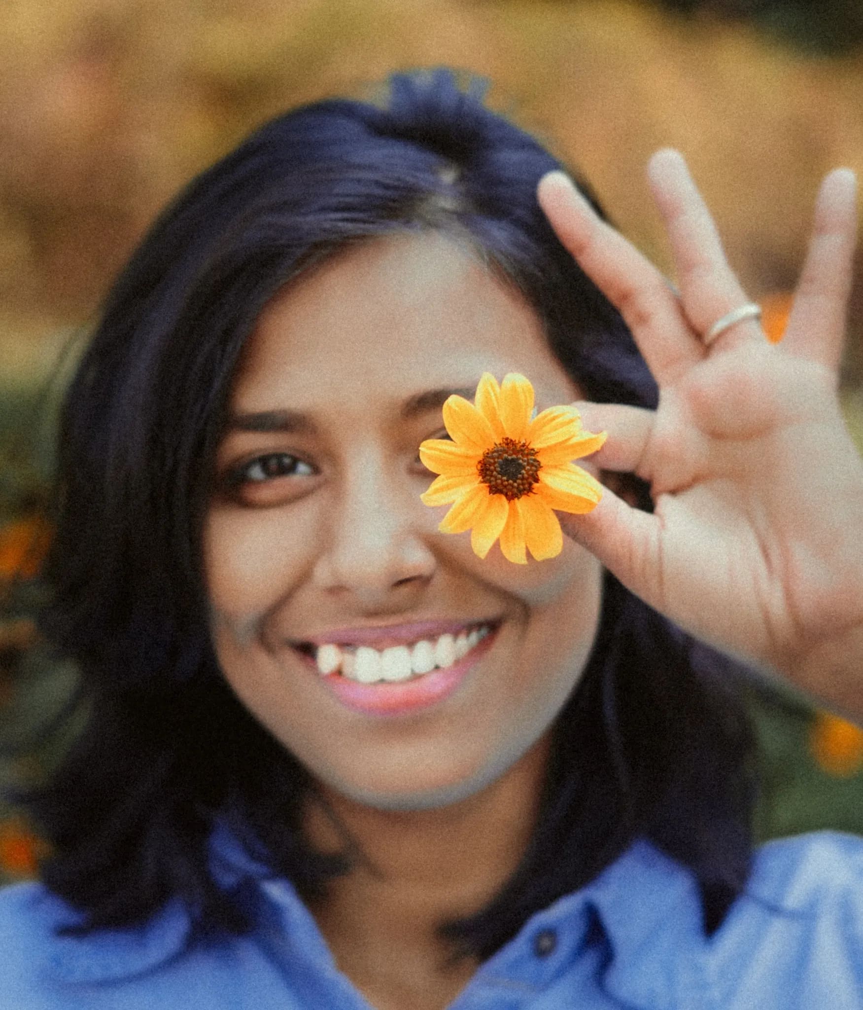 Sanmita, Creative Head at Piixonova, playfully holding orange flower over her eye, smiling outdoors, Kolkata